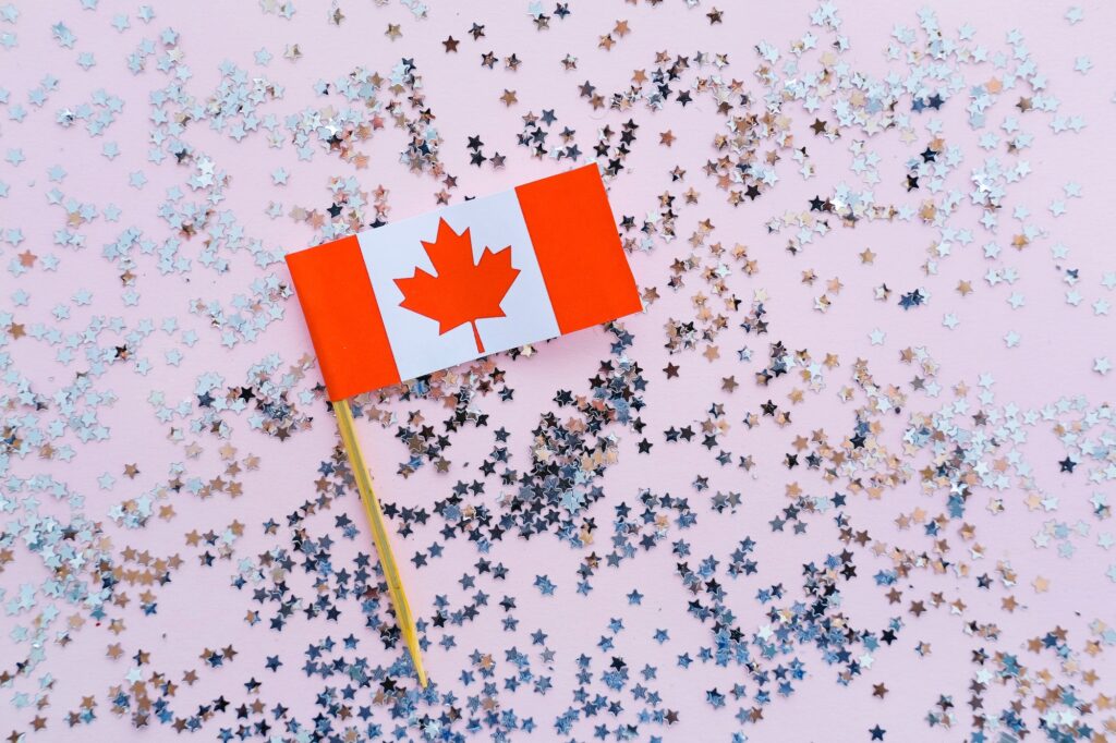 Canada flag and sparkles on pink background, flat lay. Holiday in Canada.
